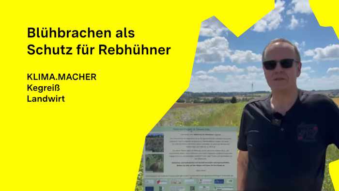 Landwirt Kegreiß steht in einer Blühbrache neben einer Infotafel.