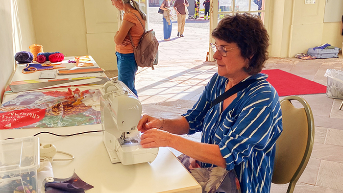 Upcycling-Workshop der „Materialmafia“: Frau näht mit einer Nähmaschine Stoffe zusammen.