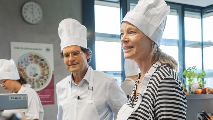 Umweltministerin Thekla Walker mit Kochmütze in der Küche des Klinikum Stuttgarts.