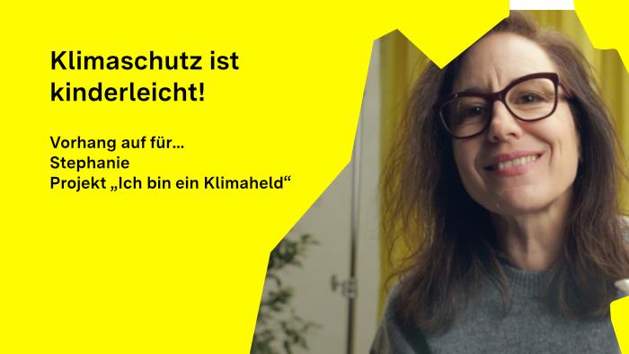 Stephanie Esch schaut in die Kamera, im Hintergrund ist ein Vorhang, im Vordergrund ein Gals mit blauer Flüssigkeit zu sehen.